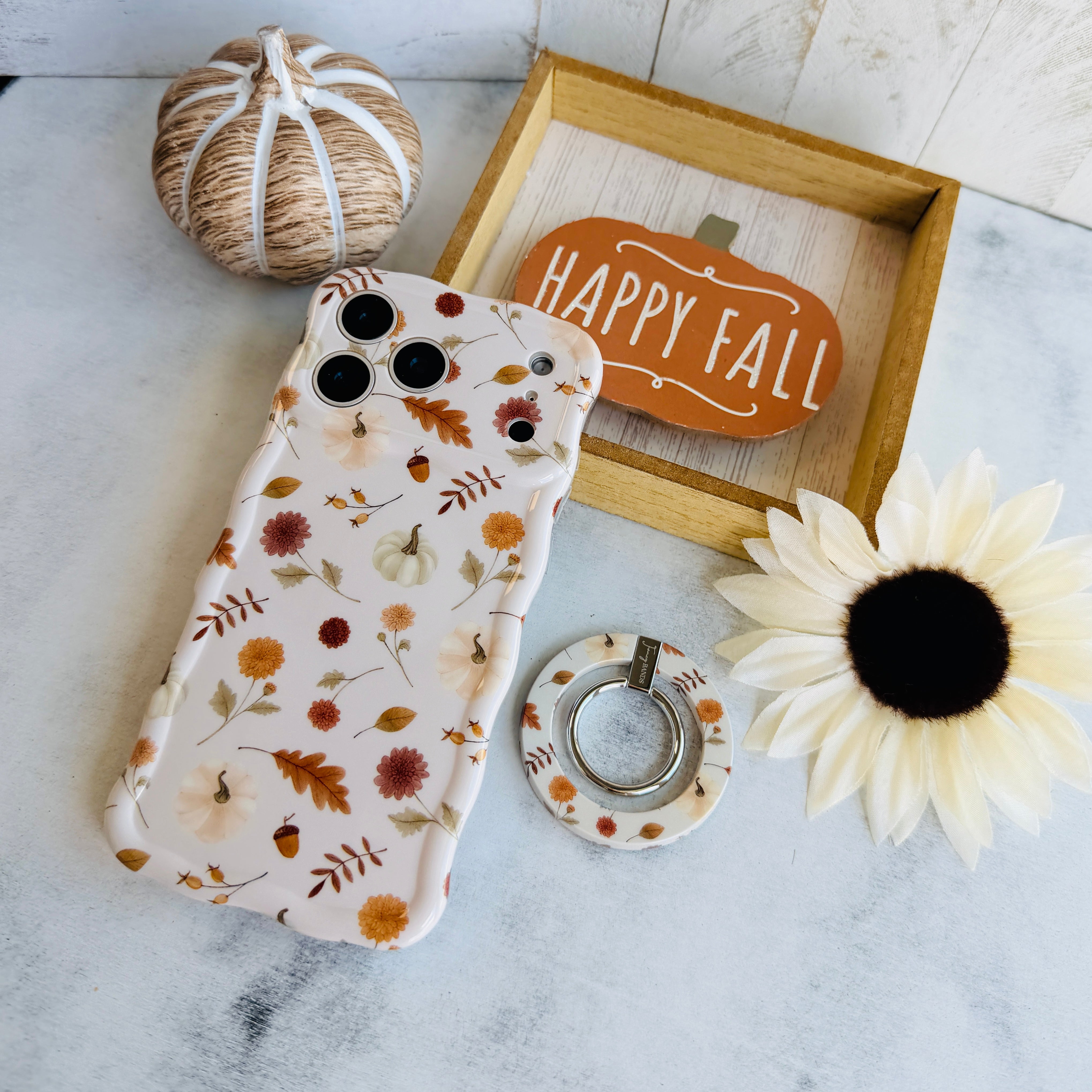 Fall Floral Bliss MagSafe grip ring shown beside the matching Fall Floral Bliss iPhone case on a fall styled flat lay with a twine pumpkin and cream sunflower.