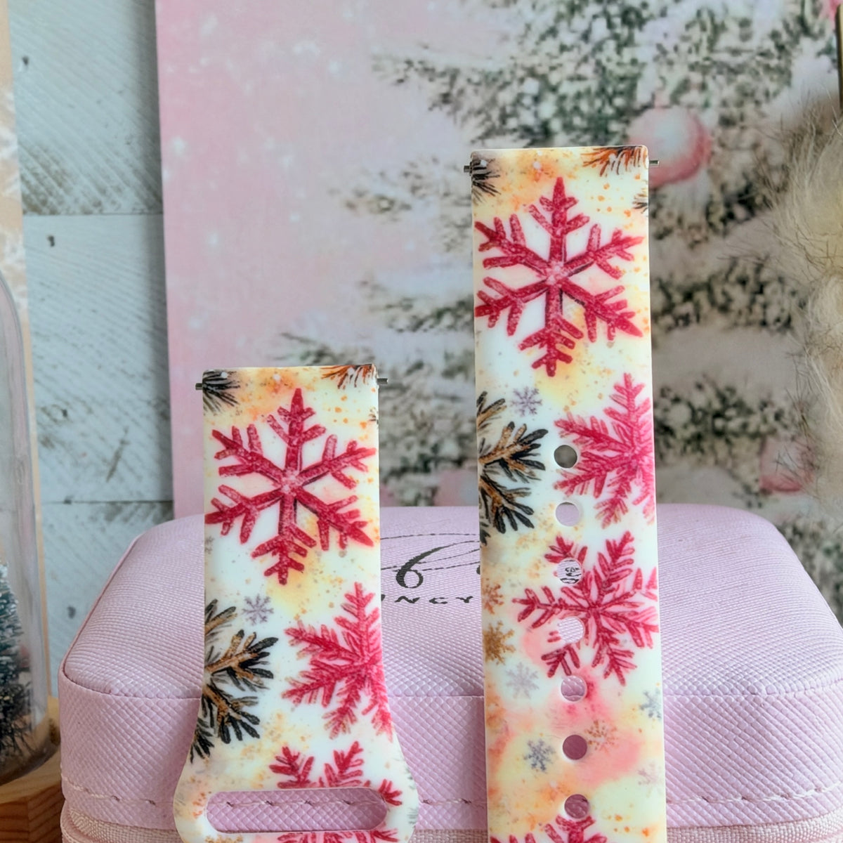 Close-up of both Champagne Snowfall Samsung Galaxy Watch band straps with glittery pink snowflakes and pine sprigs