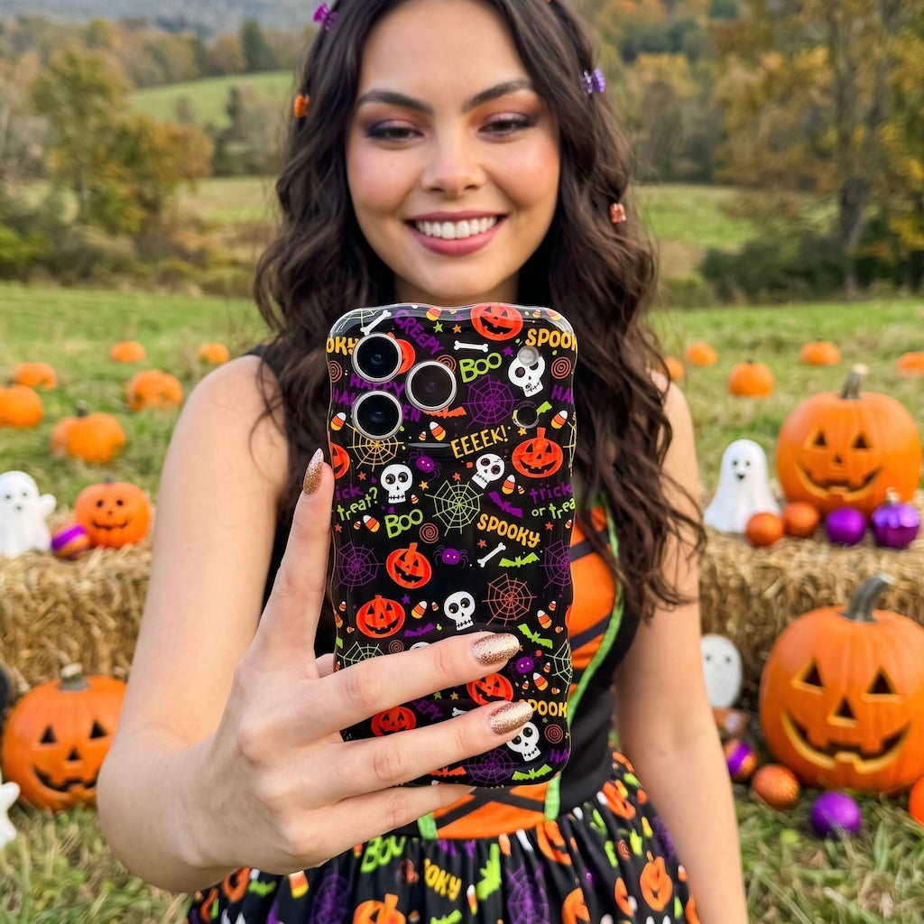 Woman holding the Spooky Wavy Luxe MagSafe iPhone case at a pumpkin patch, black case with orange pumpkins and white skulls.