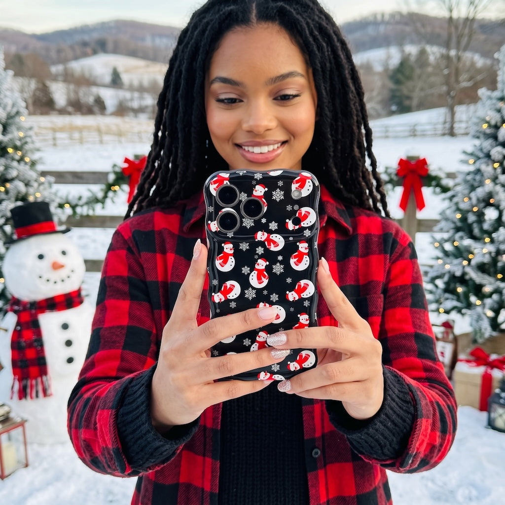 Woman with braids in a red buffalo plaid shirt holding her Snowman iPhone case in a snowy yard with a snowman