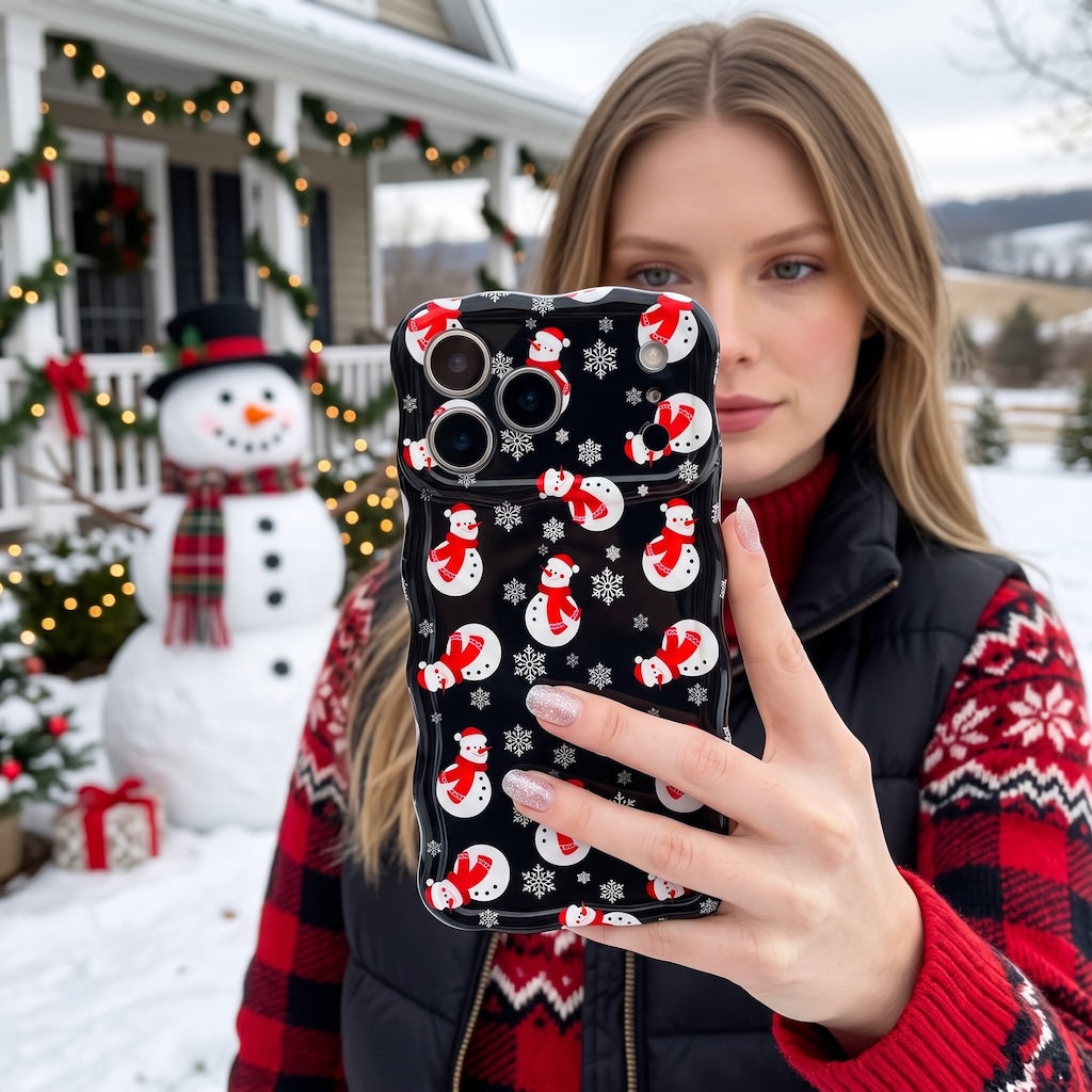 Woman in a red Fair Isle sweater holding her Snowman MagSafe iPhone case in the snow, snowman behind her
