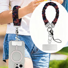 USA Fireworks scrunchie phone wrist strap worn on the wrist with a phone hanging at the hip, plus a close-up inset of the firework print strap, clasp and attachment tab.