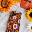 Harvest Sunflowers Wavy Luxe MagSafe iPhone case with golden sunflowers and white daisies on chocolate brown, styled with fall decor