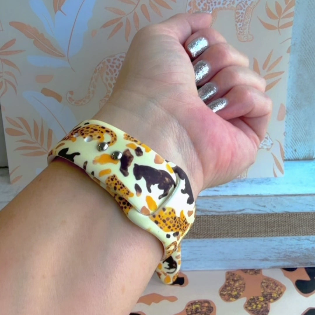 Golden Wildcat Apple Watch band with spotted leopards in golden and brown tones on cream background with safari wallpaper
