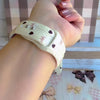 Video showing the Sweater Weather Sweetheart silicone Apple Watch band from multiple angles, featuring the cream cable-knit print with taupe bows and brown hearts.