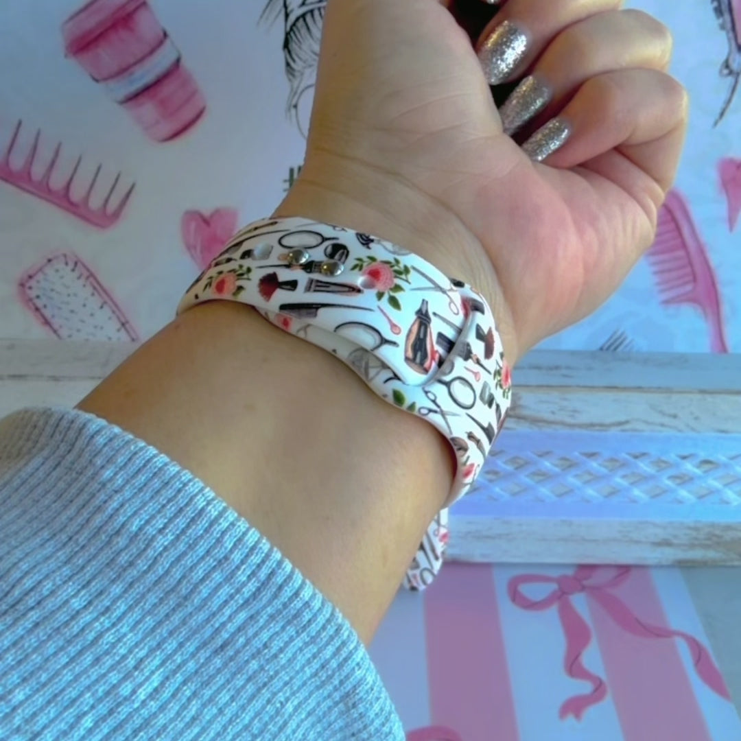 Hair Whisperer Apple Watch band with hairstyling tools, scissors, combs, and roses on white background with #HAIRLIFE backdrop
