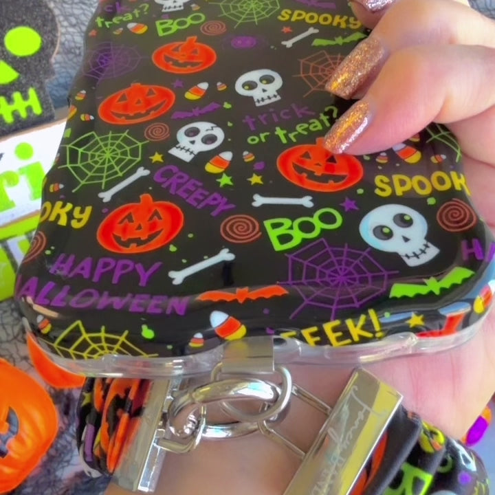 Video of the Spooky scrunchie phone wrist strap clipped to the matching case and worn on the wrist, showing the black pumpkin and skull print.
