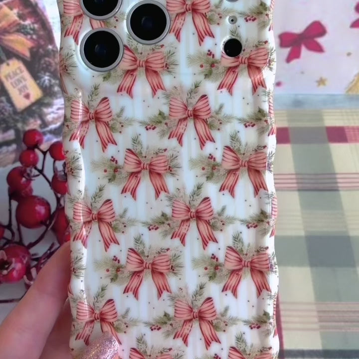 Video: turning the Deck Yourself in Bows & Holly Wavy Luxe iPhone case in hand to show the ribbon bow print and glossy wavy edges