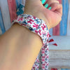 American Girly silicone Apple Watch band with red and blue coquette bows, mini cowboy boots, stars, and "American Girly" script on a white base, shown displayed and worn on Apple Watch against a patriotic 4th of July backdrop.
