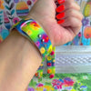 Petal Princess Apple Watch band with vibrant watercolor flowers in red, orange, yellow, pink, and blue on green background
