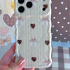 Video showing the Sweater Weather Sweetheart Wavy Luxe MagSafe iPhone case from multiple angles, featuring the cream cable-knit print with taupe bows and brown hearts.