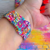 Love Riot Apple Watch band with colorful graffiti "LOVE" text in red, pink, yellow, blue, and turquoise with street art backdrop
