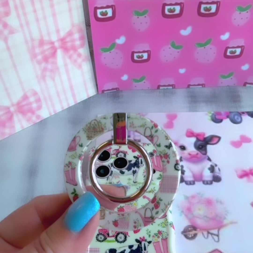 Farm Girl Cutie cottagecore MagSafe phone grip ring with pink watering cans, strawberries, rain boots, and gingham patterns on an off-white background compatible with iPhone and Samsung