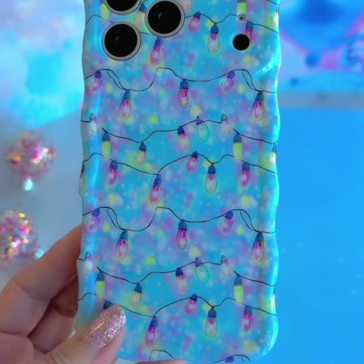 Video: turning the Twinkle All The Way Wavy Luxe iPhone case in hand to show the glossy wavy edges and pastel string lights print