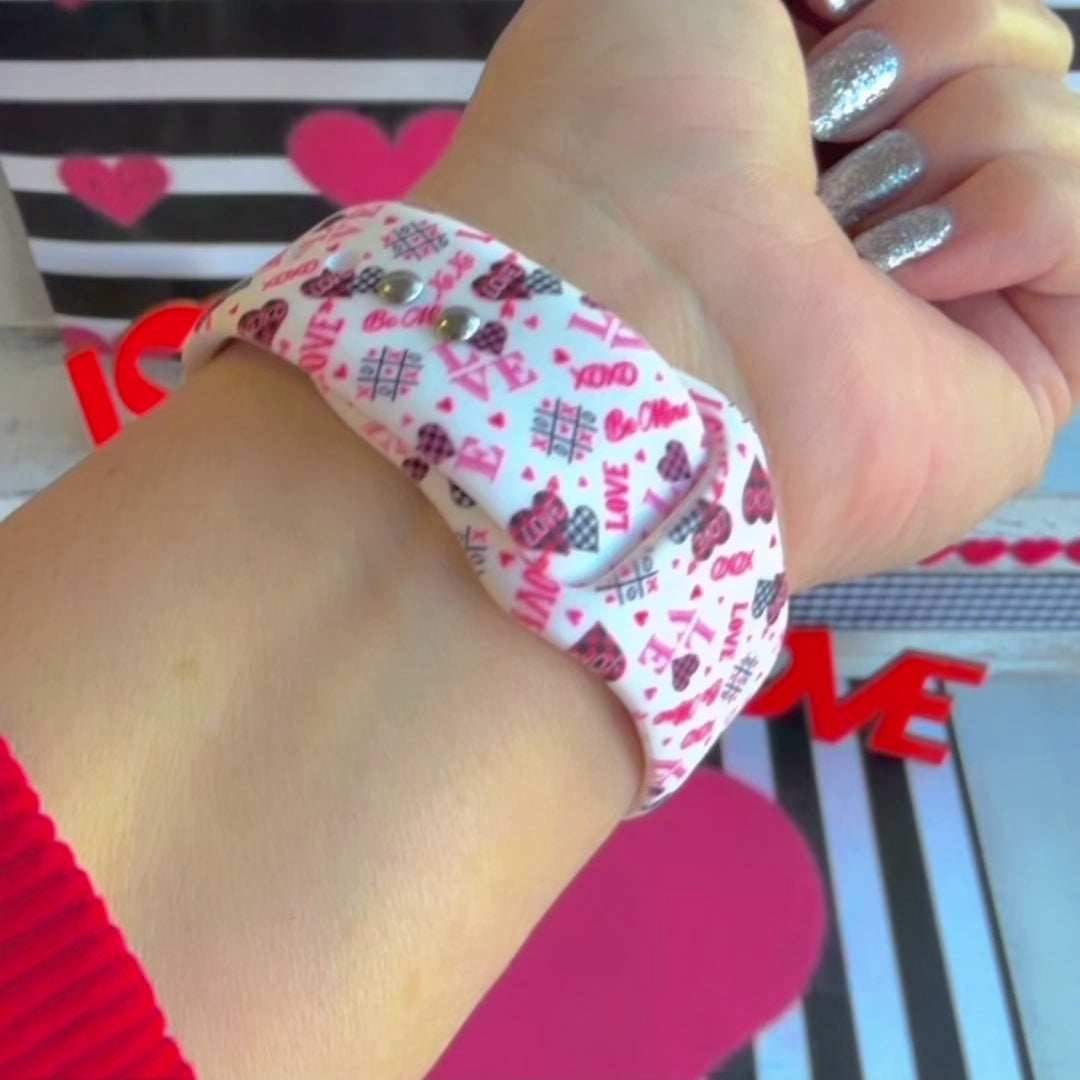 Tick-Tack-Love Apple Watch band with LOVE text, XOXO, and hearts in pink and red on white background with Valentine's decor
