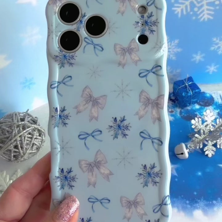 Video: turning the Snow Pretty In Blue Wavy Luxe iPhone case in hand to show the bow and snowflake print and glossy wavy edges