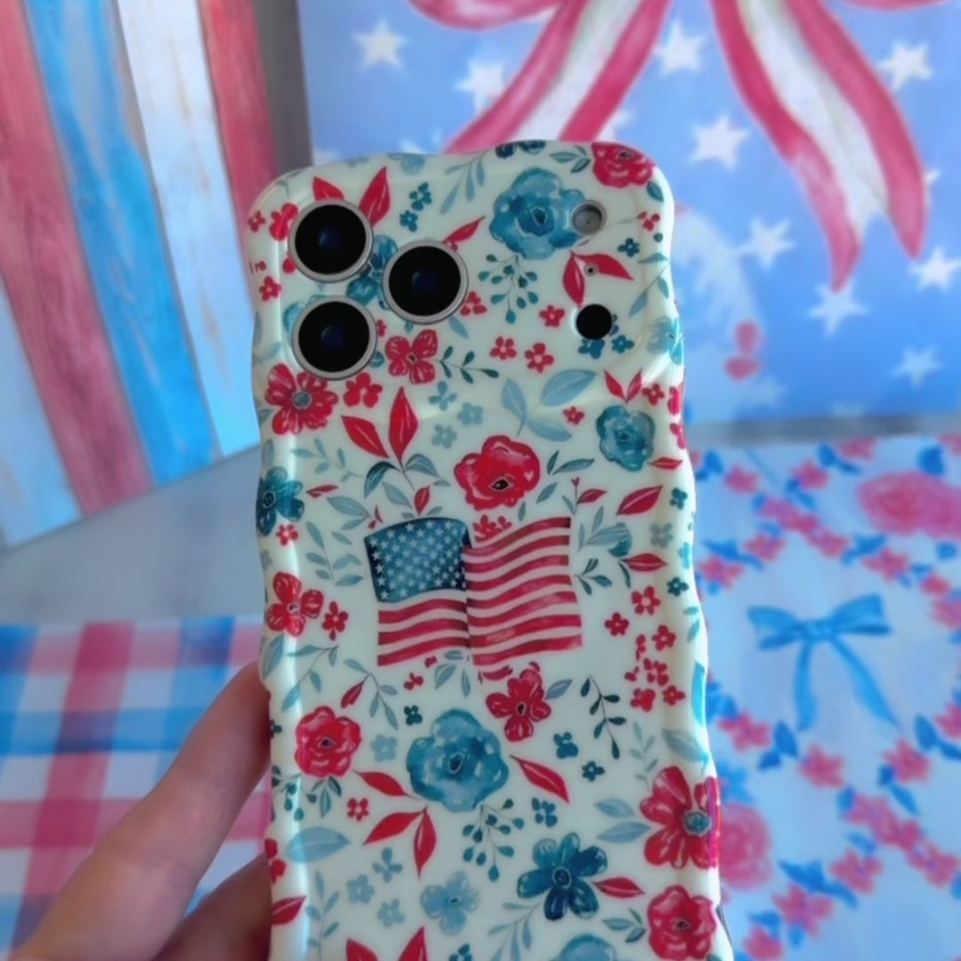 Trendy wavy iPhone case featuring an American flag illustration surrounded by a red and blue watercolor floral pattern with a high-gloss finish.