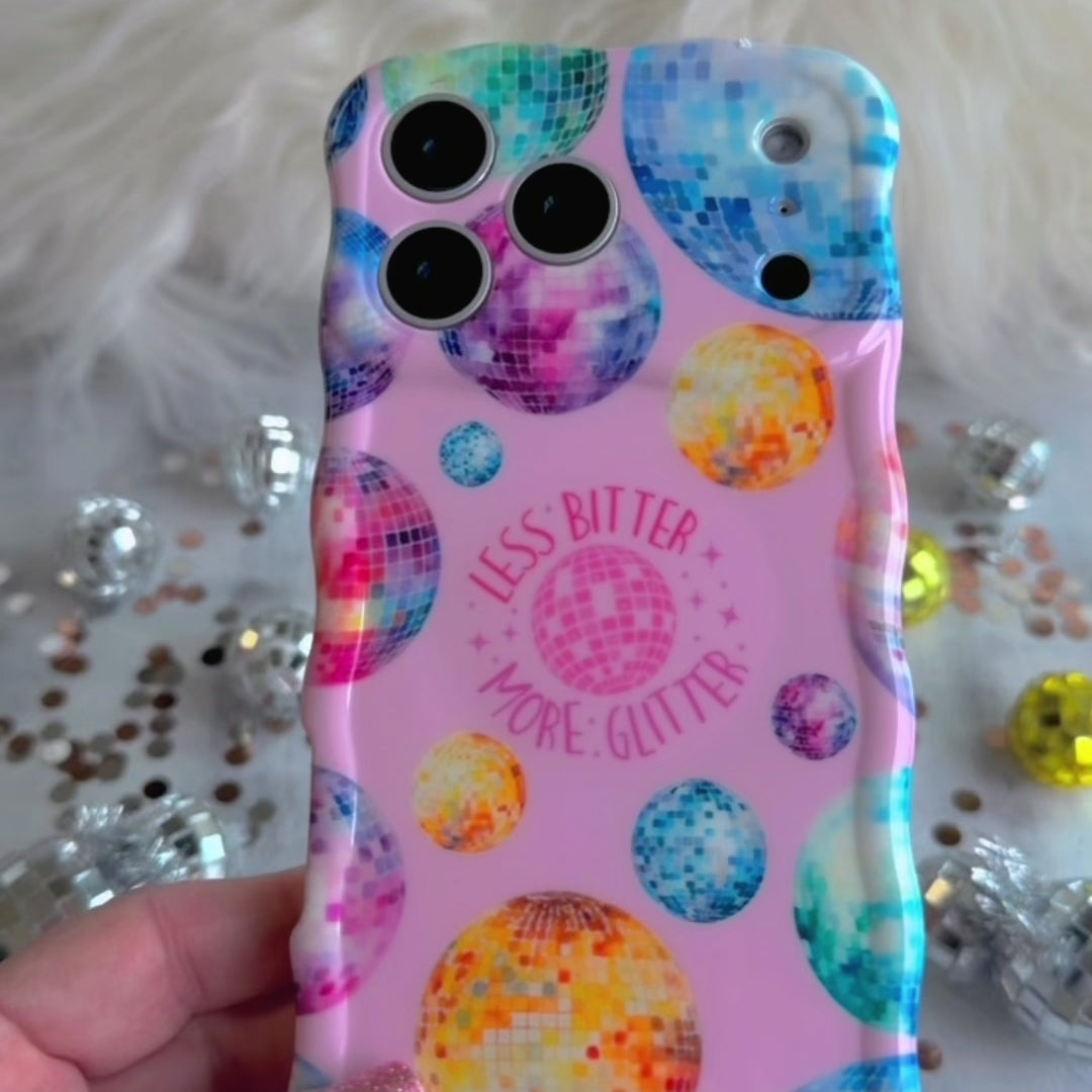 Pink wavy iPhone case featuring colorful retro disco balls and the quote Less Bitter More Glitter, held in hand with MagSafe compatibility.