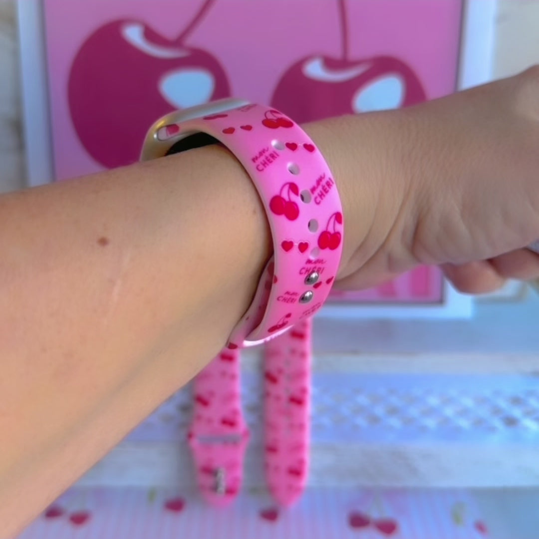 Mon Cheri Apple Watch band with red cherries, hearts, and French text on pink background with CHERI sign
