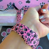 Pretty Little Paws Apple Watch band with black paw prints and polka dot bow on pink background with paw decorations
