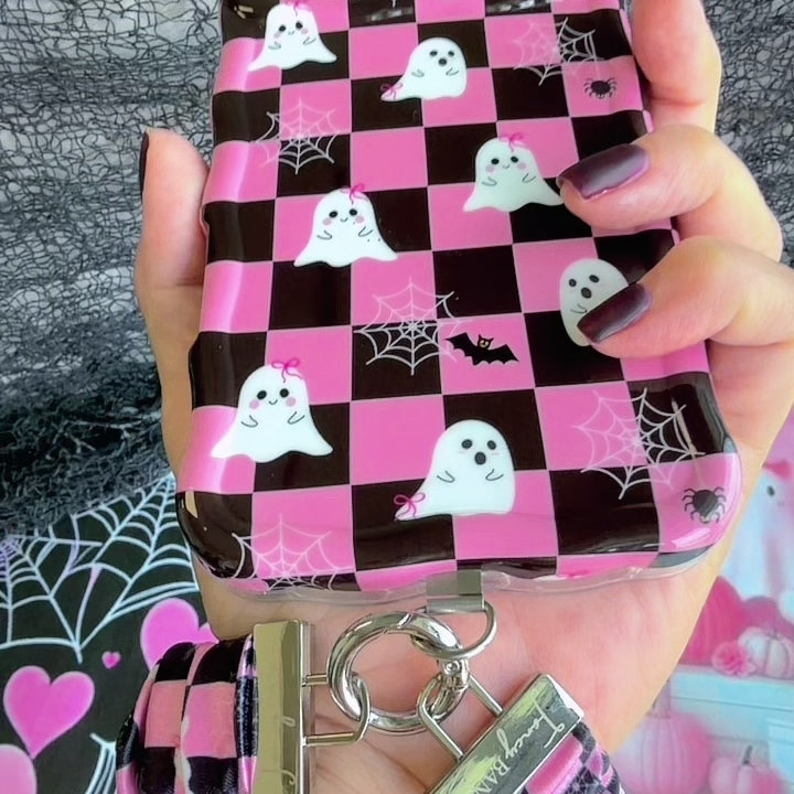 Video of the Hey Boo, Looking Cute Scrunchie Phone Wrist Strap being clipped to a phone case and worn on the wrist, showing the gathered pink checkerboard fabric and metal clasp.