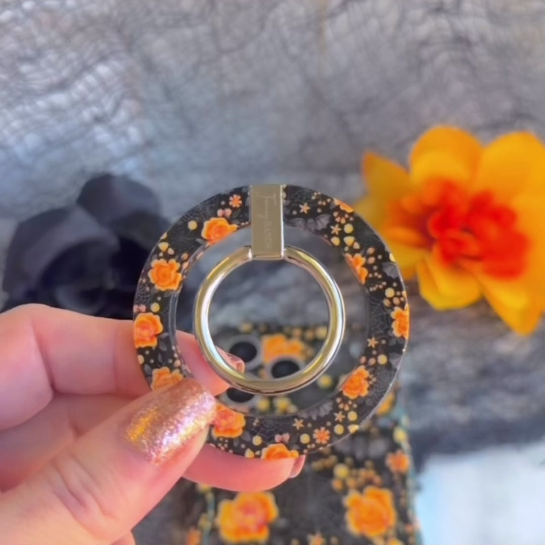 Video demo of the Haunted Blossoms MagSafe grip ring snapping onto the matching black gothic floral case, then used as a finger hold and kickstand.