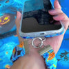 Video of The Bewitching Hour Scrunchie Phone Wrist Strap being clipped to a phone case and worn on the wrist, showing the gathered blue witch print fabric and metal clasp.