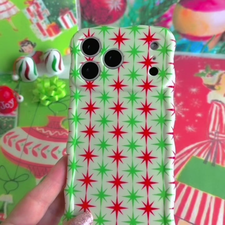 Video: turning the Tinsel & Stardust Wavy Luxe iPhone case in hand to show the red and green starburst print and glossy wavy edges