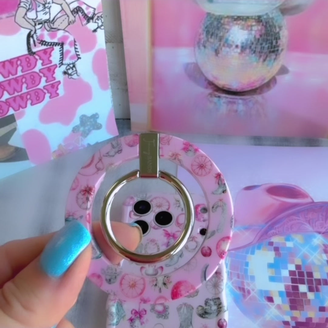 Disco Cowgirl phone grip ring with pink disco balls, cowboy boots, ribbons, and horseshoes on a light pink background compatible with iPhone and Samsung