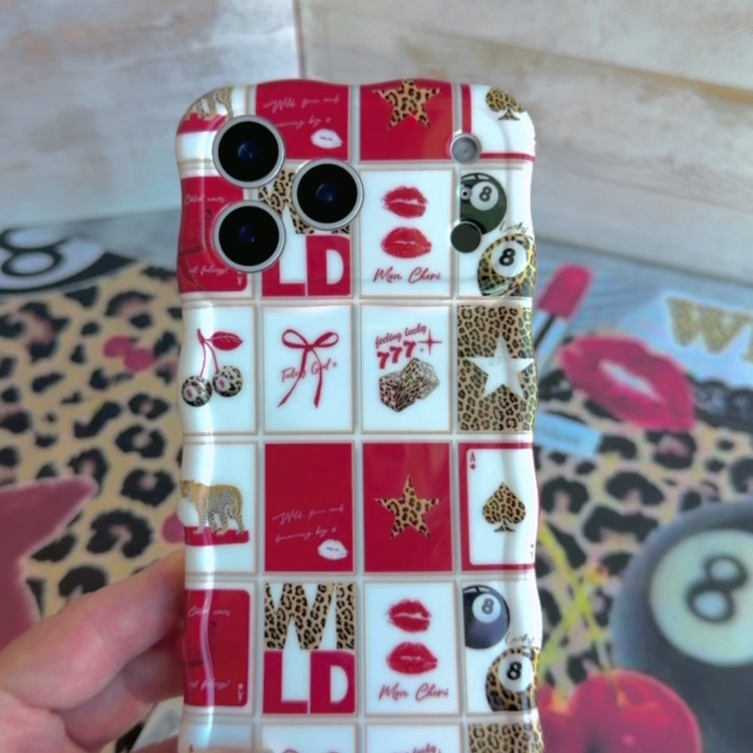 Trendy red and white wavy iPhone case featuring a collage of leopard print cherries, 8-balls, red lips, and lucky 777 dice with a high-gloss finish.
