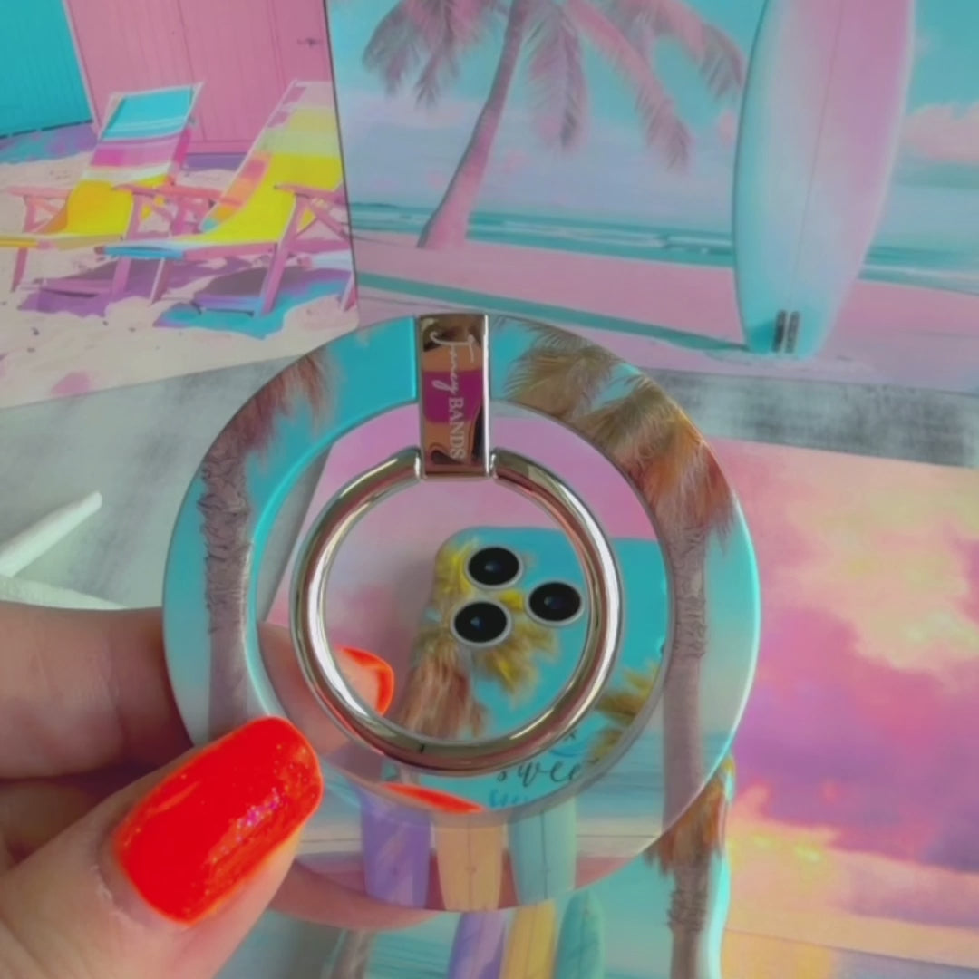 Sweet Summer MagSafe phone grip ring featuring surfboards leaning against palm trees on a tropical beach with ocean waves and a blue sky