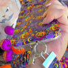 Video of the Jack-O-Lantern Jive scrunchie phone wrist strap clipped to the matching case and worn on the wrist, showing the violet neon pumpkin print.