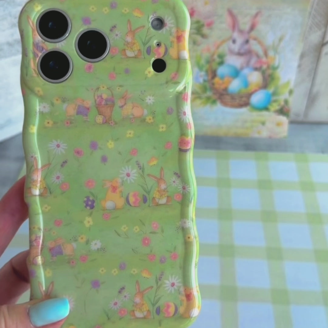 Sage green wavy iPhone case featuring a vintage watercolor pattern of bunnies, Easter eggs, and spring flowers.