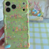 Sage green wavy iPhone case featuring a vintage watercolor pattern of bunnies, Easter eggs, and spring flowers.