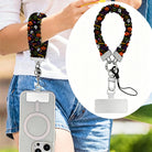 Spooky scrunchie phone wrist strap worn on the wrist and clipped at the hip, with a close-up of the black pumpkin and skull print